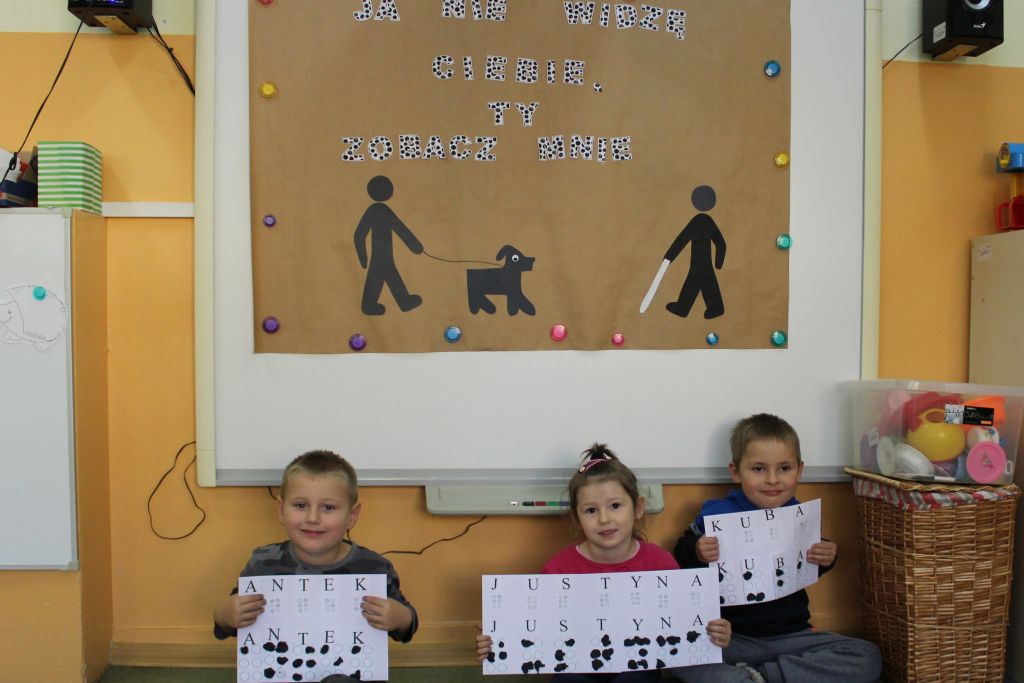 Dzieci pokazują swoje imiona napisane alfabetem Braille'a