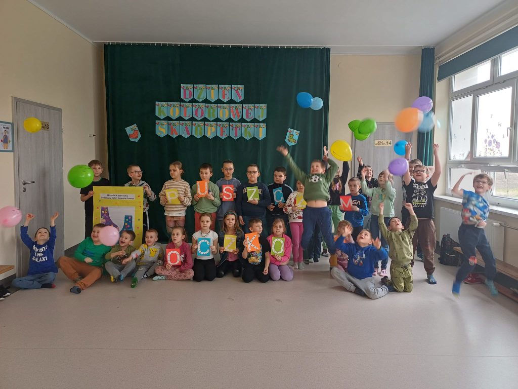 Dzieci przy napisie z balonikami